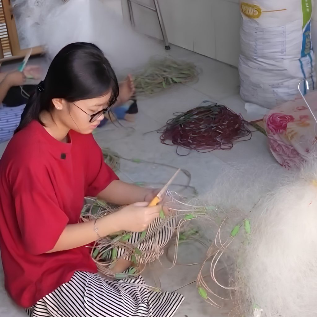 alt="Em Bùi Thị Tuyết Vy phụ giúp cha mẹ đan lưới đánh cá tại TP.HCM"